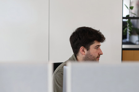 Person sitzt hinter zwei Bildschirmen.
